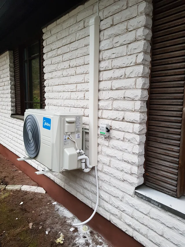 Midea-ilmalämpöpumpun ulkoyksikkö vaalealla tiiliseinällä.