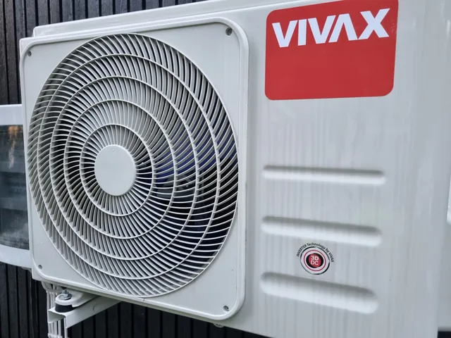 Vivax-ilmalämpöpumpun ulkoyksikkö tummalla puuseinällä.
